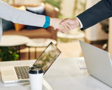 Close-up image of businessman and businesswoman shaking hands after discussing work at meeting
